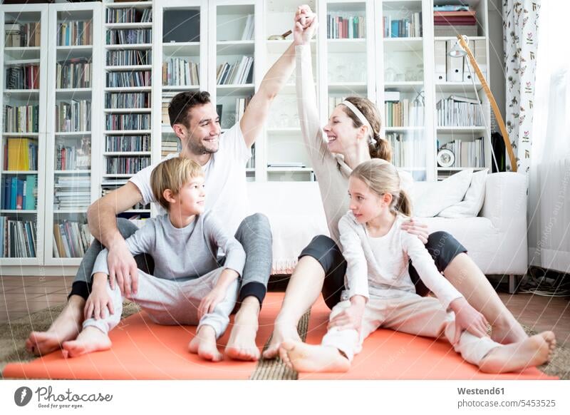 Glückliche Familie macht zu Hause Gymnastik Zuhause daheim lächeln Familien Fitness fit Gesundheit gesund sportlich Mensch Menschen Leute People Personen Sport