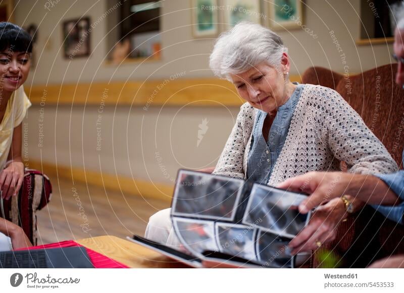 Senioren im Altersheim beim Betrachten von Fotoalben Fotos Aufenthaltsraum Gemeinschaftsraum Seniorin älter Seniorinnen ansehen Fotoalbum Altenheim Seniorenheim