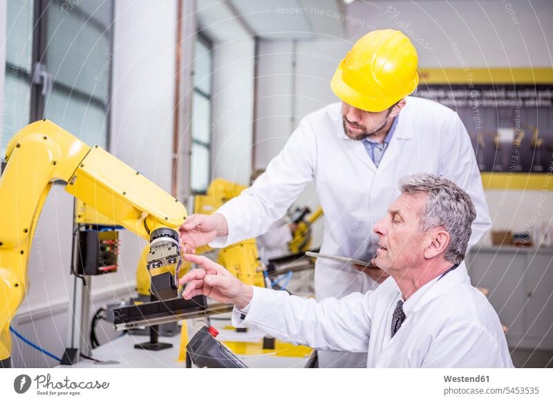 Zwei Ingenieure untersuchen Industrieroboter Mann Männer männlich Kollegen Arbeitskollegen Roboter Fabrik Fabriken Erwachsener erwachsen Mensch Menschen Leute