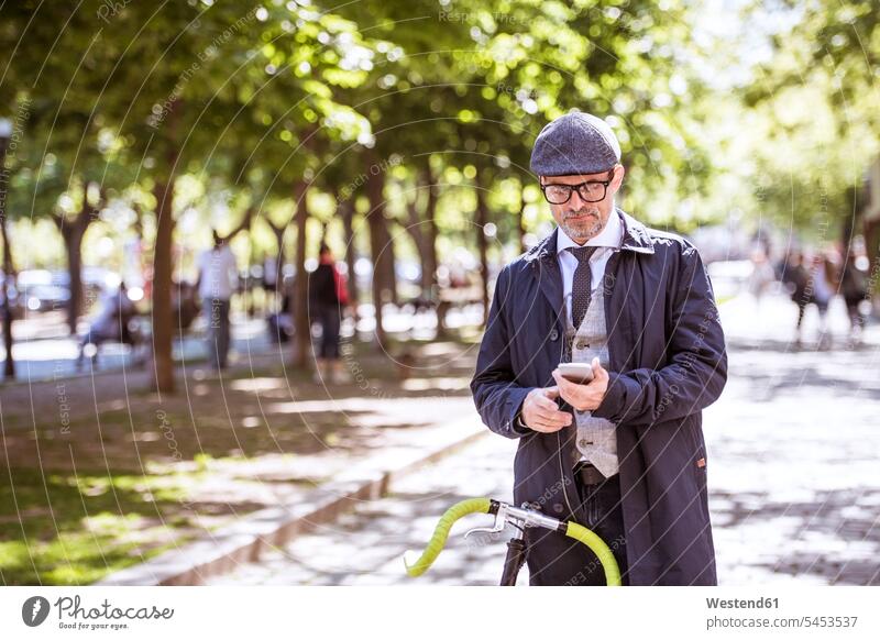 Älterer Geschäftsmann mit Fahrrad und Smartphone in der Stadt Handy Mobiltelefon Handies Handys Mobiltelefone Bikes Fahrräder Räder Rad telefonieren anrufen