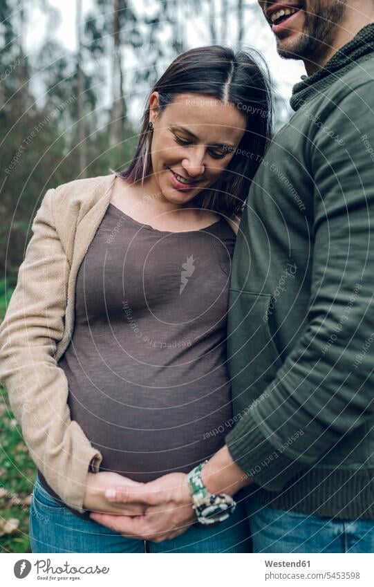 Mann mit lächelnder schwangerer Frau in der Natur Paar Pärchen Paare Partnerschaft Schwangere schwangere Frau Mensch Menschen Leute People Personen stehen