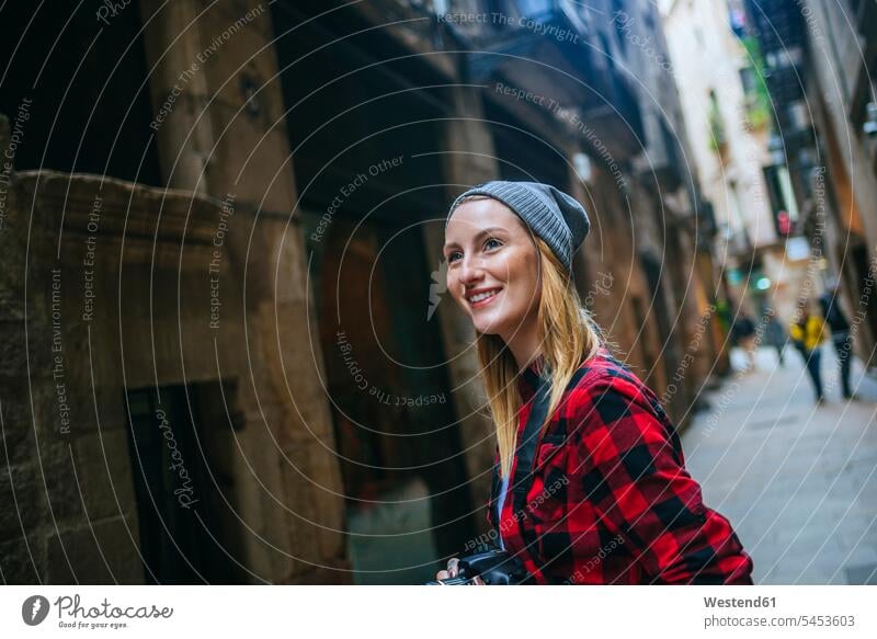 Spanien, Barcelona, Porträt einer lächelnden jungen Frau mit Kamera im Gothic-Viertel weiblich Frauen Touristin Portrait Porträts Portraits Erwachsener