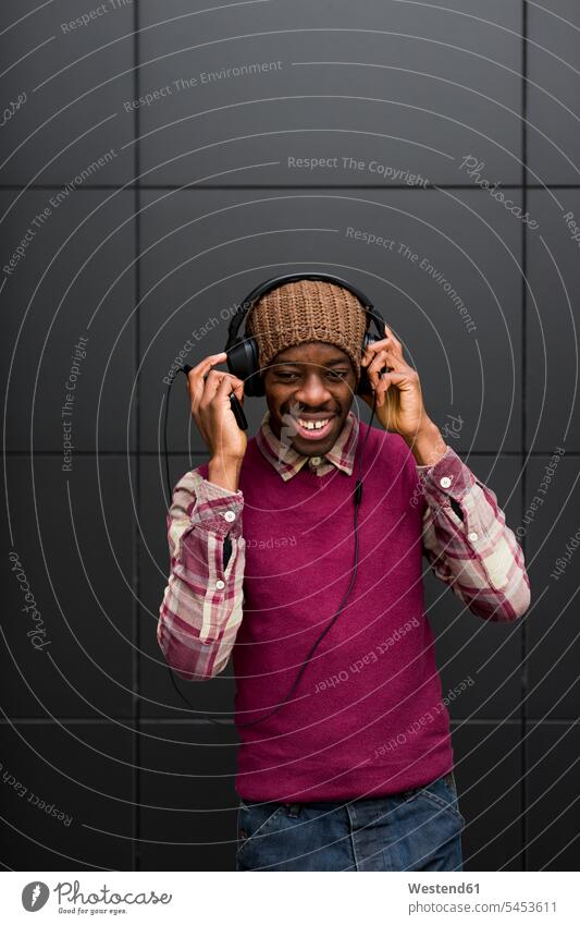 Porträt eines lächelnden Mannes, der mit Kopfhörer und Handy Musik hört Männer männlich Kopfhoerer Erwachsener erwachsen Mensch Menschen Leute People Personen