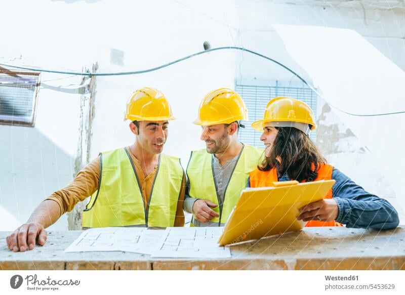 Frau zeigt zwei Bauarbeitern auf der Baustelle die Zwischenablage Kollegen Arbeitskollegen Baustellen Handwerker Handwerksberuf Handwerksberufe Gewerbe