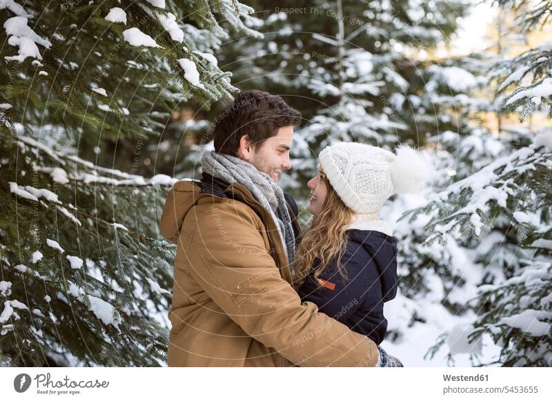Glückliches junges Paar von Angesicht zu Angesicht im schneebedeckten Winterwald Pärchen Paare Partnerschaft Mensch Menschen Leute People Personen Schnee