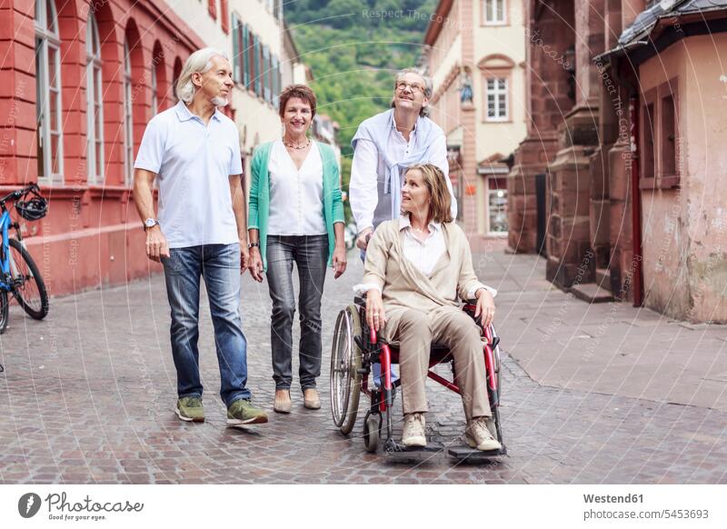Deutschland, Heidelberg, ältere Freunde mit Frau im Rollstuhl auf Städtereise lächeln Senioren alte Freundschaft Kameradschaft Erwachsene erwachsen Mensch