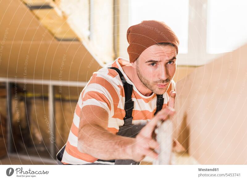Junger Mann überprüft Planke auf der Baustelle Eigenheim Eigenheime wohnen junger Mann junge Männer schreinern Heimwerken Do-it-Yourself DIY renovieren