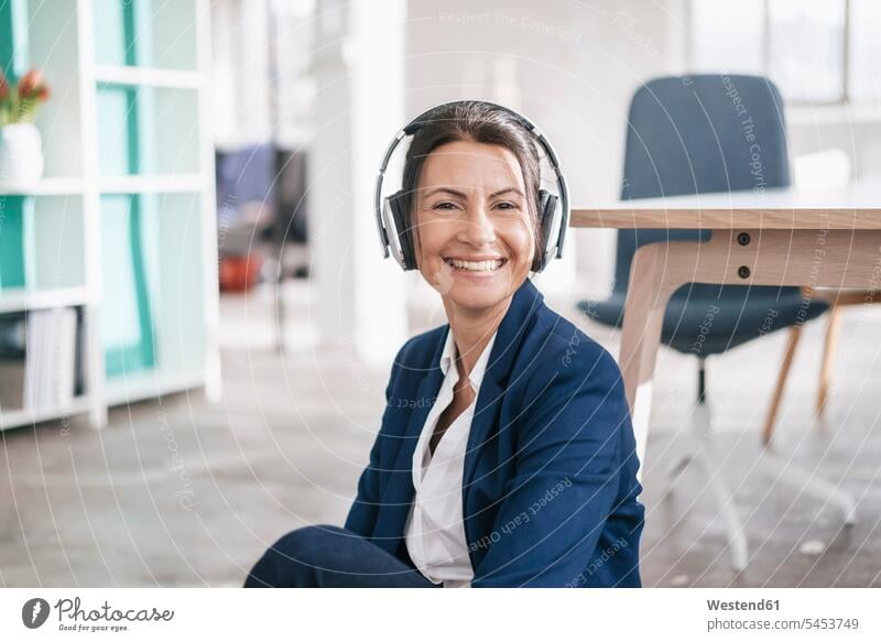 Porträt einer glücklichen Geschäftsfrau in einem Loft, die mit Kopfhörern Musik hört Portrait Porträts Portraits Frau weiblich Frauen Geschäftsfrauen