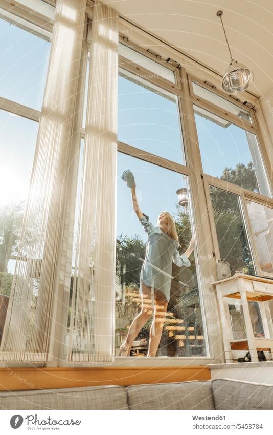 Frau putzt das Fenster bei Sonnenschein putzen reinigen weiblich Frauen Erwachsener erwachsen Mensch Menschen Leute People Personen Zuhause zu Hause daheim