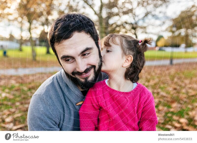 Kleines Mädchen küsst ihren glücklichen Vater im herbstlichen Park küssen Küsse Kuss Tochter Töchter Papas Väter Vati Vatis Papis Kind Kinder Familie Familien