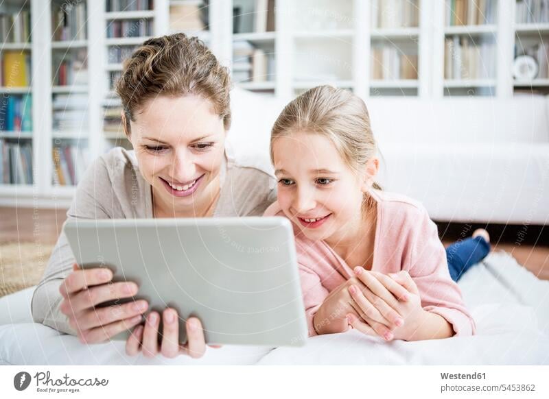 Mutter und Tochter verwenden Tabletten zu Hause Zuhause daheim Töchter lächeln Mami Mutti Mütter Mama Familie Familien Tablet Computer Tablet-PC Tablet PC iPad