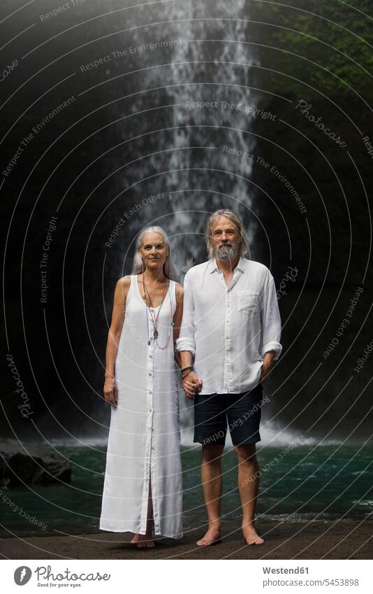 Zärtliches älteres Ehepaar steht vor einem tropischen Wasserfall Hände halten Haendchen halten Hand halten Haende halten Händchen halten Hand in Hand Paar