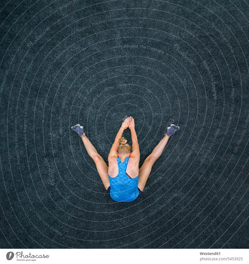 Junge Frau beim Turnen, Draufsicht Sportlerin Sportlerinnen Gymnastik Fitnesstraining fit Gesundheit gesund Boden Grund Land sitzen sitzend sitzt Stretching