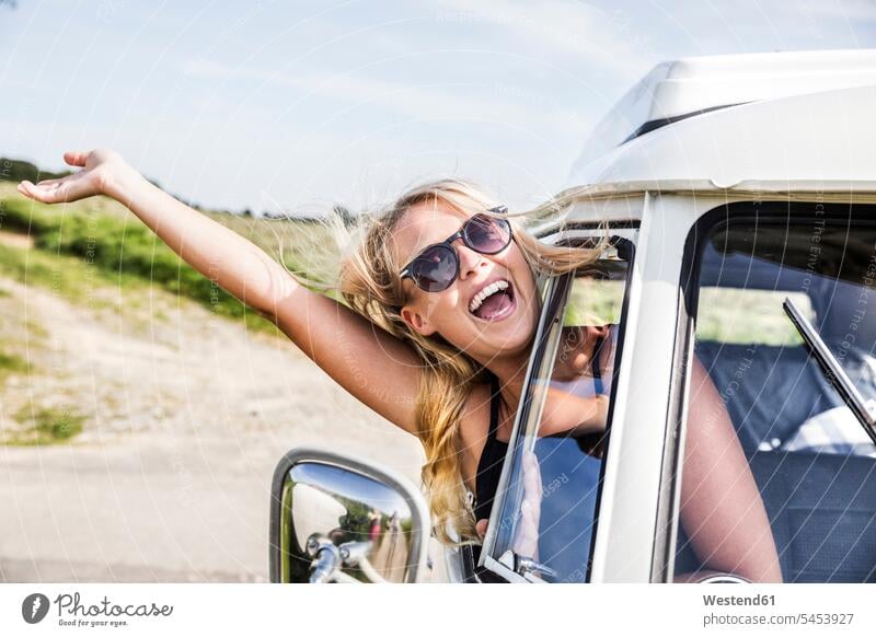Sorglose Frau lehnt sich aus dem Fenster eines Lieferwagens Spaß Spass Späße spassig Spässe spaßig Kleinbus Kleinbusse lachen weiblich Frauen ländlich