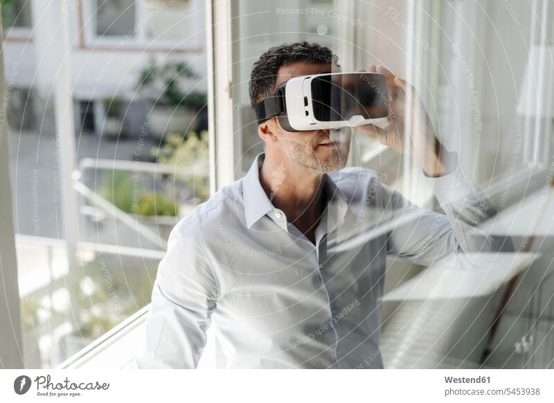 Geschäftsmann am Fenster mit VR-Brille Büro Office Büros Virtual Reality Virtuelle Realität Businessmann Businessmänner Geschäftsmänner Arbeitsplatz
