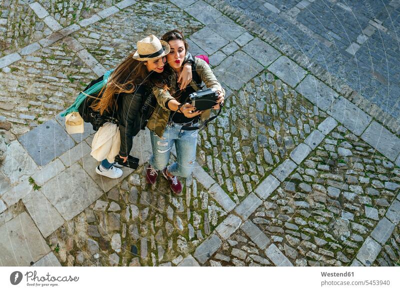 Zwei glückliche junge Frauen machen ein Selfie mit einer Kamera lächeln Selfies Freundinnen fotografieren Freunde Freundschaft Kameradschaft Kameras umarmen