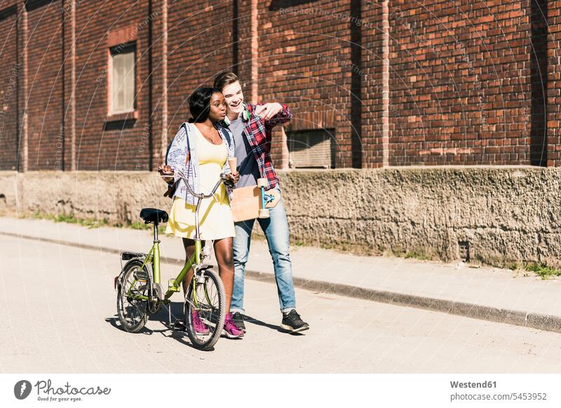 Junges Paar mit Fahrrad und Skateboard macht Smartphone-Selfies iPhone Smartphones Handy Mobiltelefon Handies Handys Mobiltelefone jung fröhlich Fröhlichkeit