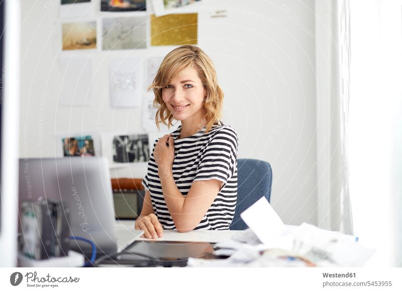 Porträt einer lächelnden blonden Geschäftsfrau mit Laptop, am Schreibtisch sitzend Frau weiblich Frauen blonde Haare blondes Haar Arbeitstisch Schreibtische