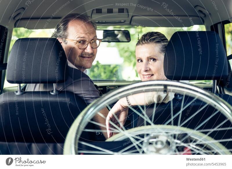 Lächelndes Paar im Auto mit Rollstuhl im Kofferraum Wagen PKWs Automobil Autos lächeln Pärchen Paare Partnerschaft Senioren alte ältere Kraftfahrzeug