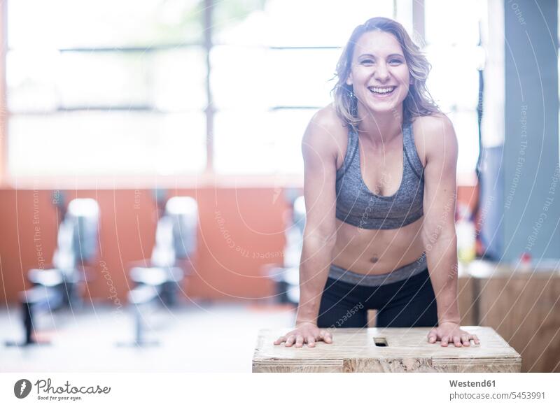 Porträt einer glücklichen jungen Frau im Fitnessstudio Fitnessclubs Fitnessstudios Turnhalle lächeln trainieren weiblich Frauen fit Gesundheit gesund Sport