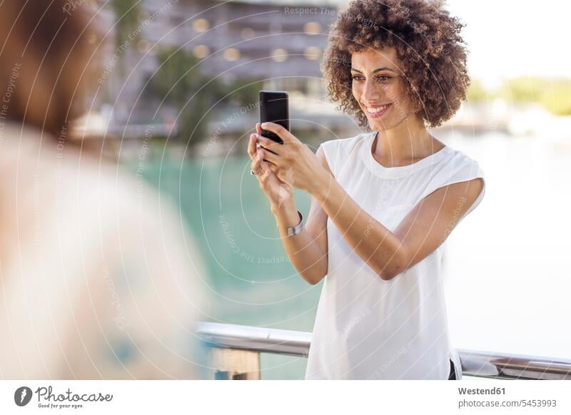 Junge Frau macht ein Selfie mit ihrem Smartphone Handy Mobiltelefon Handies Handys Mobiltelefone weiblich Frauen Geländer Selfies glücklich Glück glücklich sein
