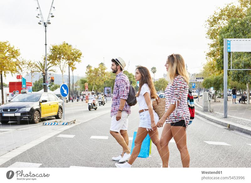 Drei Freunde überqueren eine Straße Strassen Straßen gehen gehend geht Freundschaft Kameradschaft Freizeitkleidung casual Freizeitbekleidung reisen Travel