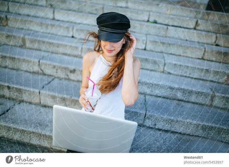 Junge Frau mit Laptop und Smoothie auf der Treppe sitzend weiblich Frauen Notebook Laptops Notebooks Treppenaufgang Erwachsener erwachsen Mensch Menschen Leute