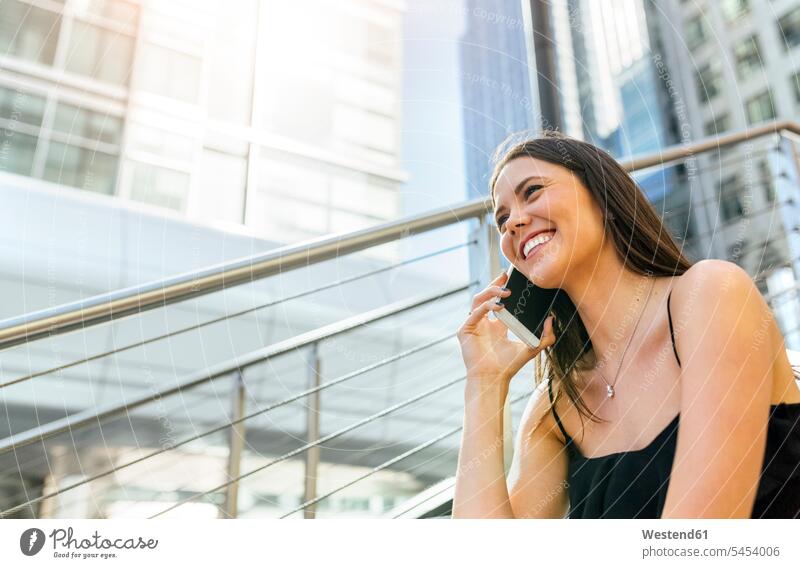 Lächelnde junge Frau am Telefon in der Stadt Handy Mobiltelefon Handies Handys Mobiltelefone weiblich Frauen telefonieren anrufen Anruf telephonieren lächeln