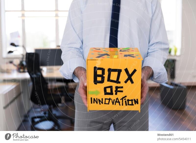 Geschäftsmann sammelt innovative Vorschläge in gelber Box Innovation Neuheit Neuerung Innovationskraft halten Boxen Kiste Schachtel Businessmann Businessmänner