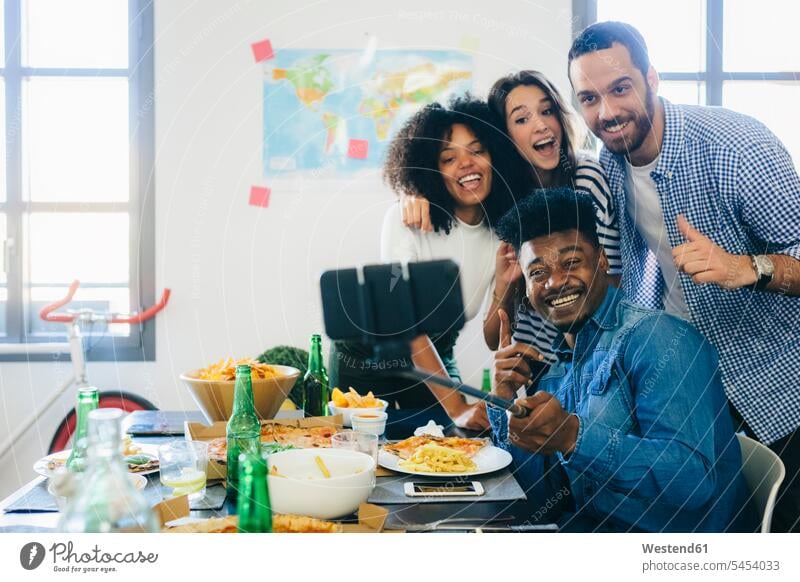 Gruppe von Freunden posiert für ein Selfie am Esstisch zu Hause Tisch Tische Spaß Spass Späße spassig Spässe spaßig Selfies Handy Mobiltelefon Handies Handys