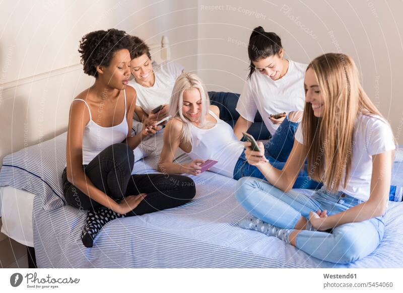 Glückliche Freundinnen benutzen Mobiltelefone im Schlafzimmer glücklich glücklich sein glücklichsein Handy Handies Handys Frau weiblich Frauen Bett Betten