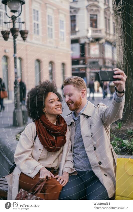 Ein glückliches Paar macht ein Selfie in der Stadt lächeln Selfies Pärchen Paare Partnerschaft Handy Mobiltelefon Handies Handys Mobiltelefone Mensch Menschen