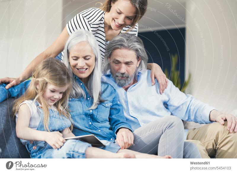 Familie sitzt auf der Couch und sieht zu, wie die Enkelin einen Tablet-PC benutzt Familien Sofa Couches Liege Sofas Zuhause zu Hause daheim sitzen sitzend