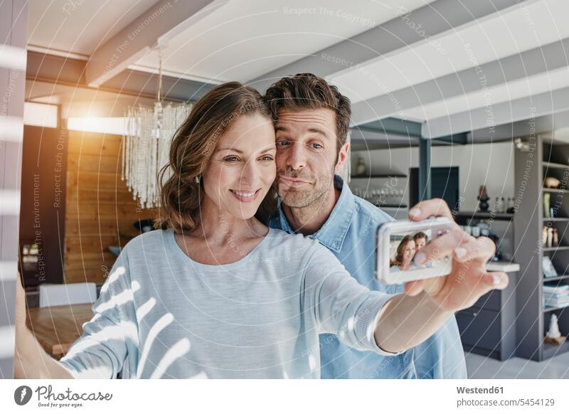 Glückliches Paar, das sich zu Hause fotografiert Selfie Selfies Pärchen Paare Partnerschaft fotografieren Foto machen Fotos machen Zuhause daheim glücklich