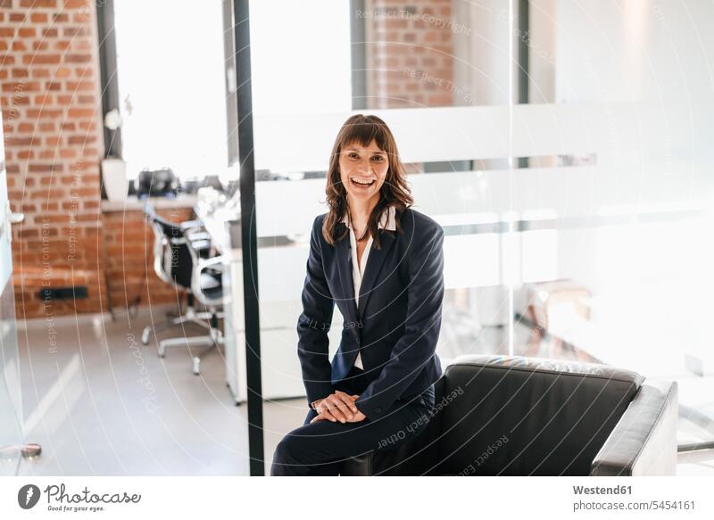 Erfolgreiche Geschäftsfrau auf Sessel sitzend lächeln Kompetenz kompetent sitzt Erfolge erfolgreich Geschäftsfrauen Businesswomen Businessfrauen Businesswoman