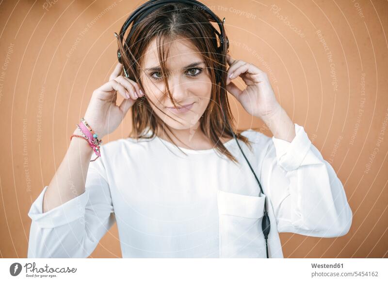 Porträt einer lächelnden jungen Frau, die mit Kopfhörern Musik hört Portrait Porträts Portraits Kopfhoerer hören hoeren weiblich Frauen Erwachsener erwachsen