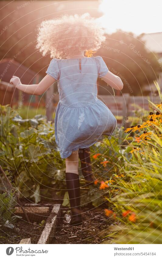 Rückenansicht eines glücklichen kleinen Mädchens, das im Garten herumspringt Blume Blumen Blüte weiblich Gärten Gaerten Kind Kinder Kids Mensch Menschen Leute