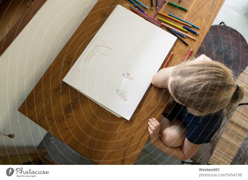 Kleines Mädchen sitzt am Tisch und zeichnet mit Buntstiften Zeichnung Zeichnungen weiblich zeichnen sitzen sitzend Tische Bild Bildnis Bilder Kind Kinder Kids