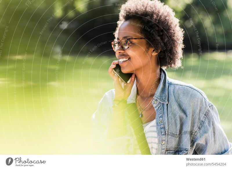 Lächelnde junge Frau ohne Mobiltelefon im Park lächeln Parkanlagen Parks weiblich Frauen telefonieren anrufen Anruf telephonieren Handy Handies Handys