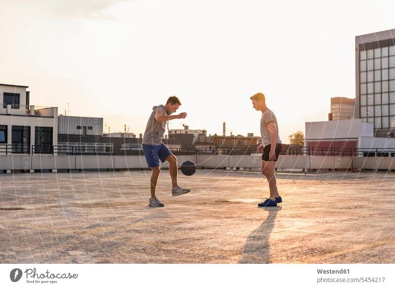 Freunde spielen bei Sonnenuntergang auf einem Dach Basketball Spaß Spass Späße spassig Spässe spaßig jung Basketbaelle Basketbälle fit Herausforderung