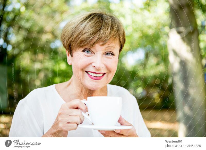 Porträt einer lächelnden älteren Frau, die im Freien eine Tasse Kaffee trinkt Seniorin Seniorinnen alt weiblich Frauen Senioren Erwachsener erwachsen Mensch