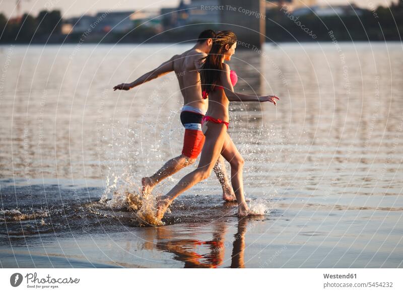 Glückliches Paar läuft im Wasser See Seen laufen rennen Spaß Spass Späße spassig Spässe spaßig Pärchen Paare Partnerschaft Gewässer Mensch Menschen Leute People