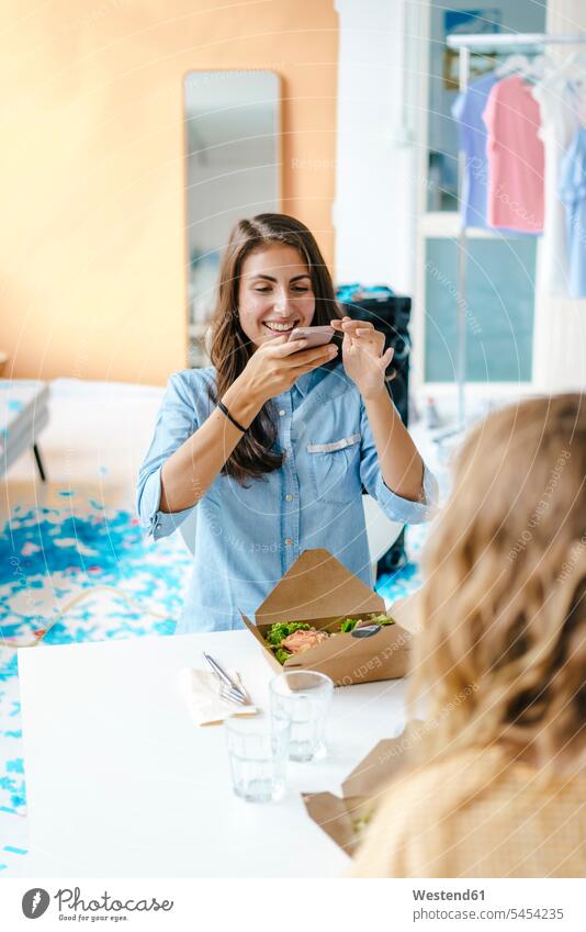 Glückliche junge Frau beim Fotografieren eines Salats zum Mitnehmen auf dem Tisch Tische glücklich glücklich sein glücklichsein Handy Mobiltelefon Handies
