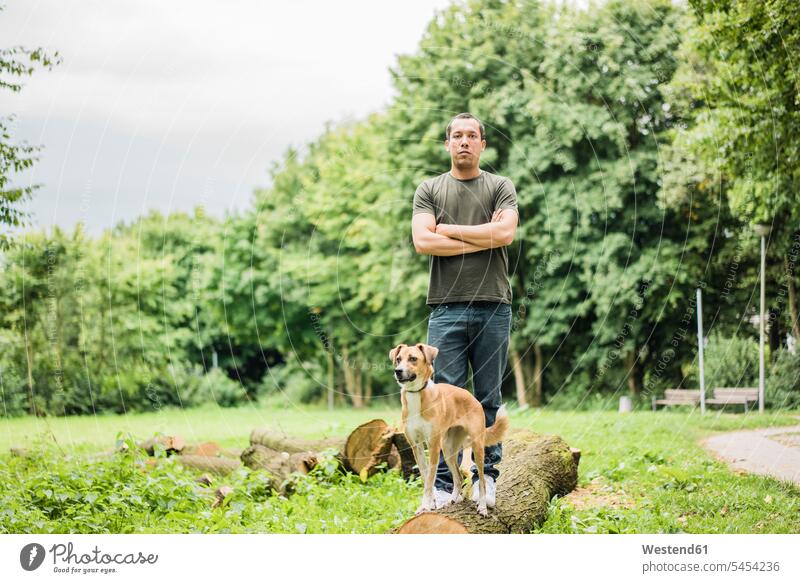 Porträt eines ernsthaften Mannes mit Hund in einem Park Portrait Porträts Portraits Männer männlich stehen stehend steht Hunde Ernst Ernsthaftigkeit Erwachsener