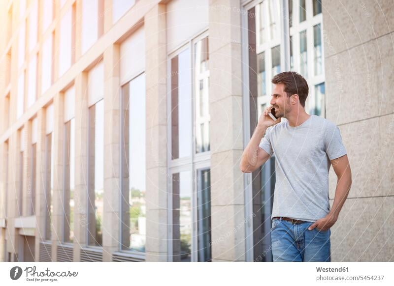 Mann geht in der Stadt spazieren, telefoniert Handy Mobiltelefon Handies Handys Mobiltelefone unterwegs auf Achse in Bewegung Männer männlich stehen stehend
