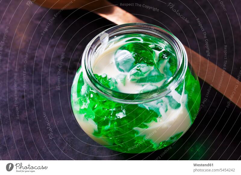 Grünes Waldmeistergelee im Glas mit Vanillesauce Götterspeise Goetterspeise Wackelpudding Wackelpeter servierfertig angerichtet Vanillesoße Gelee Nahaufnahme
