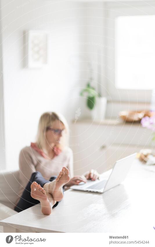 Frau sitzt am Tisch mit erhobenen Füßen am Laptop Notebook Laptops Notebooks weiblich Frauen Computer Rechner Erwachsener erwachsen Mensch Menschen Leute People