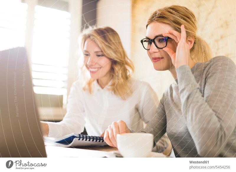 Zwei Geschäftsfrauen arbeiten gemeinsam am Laptop Notebook Laptops Notebooks Arbeit lächeln Businesswomen Businessfrauen Businesswoman Kollegin Kolleginnen
