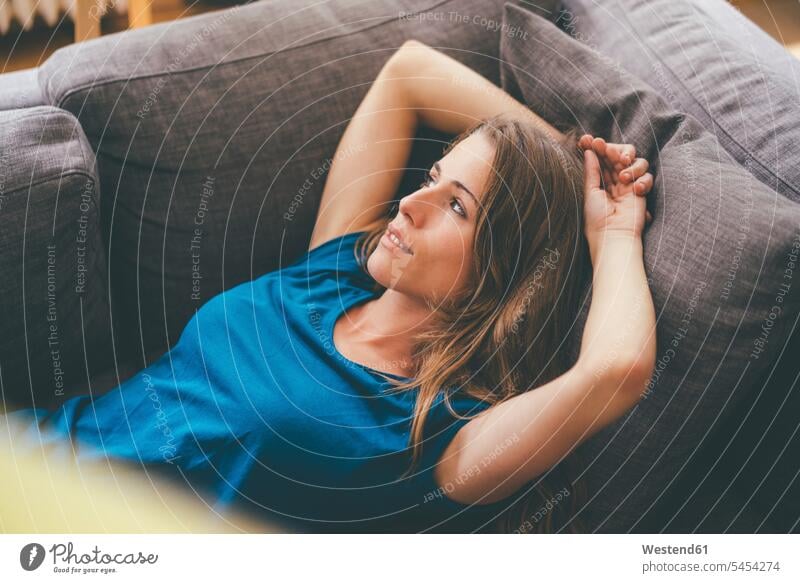 Entspannte junge Frau liegt zu Hause auf der Couch liegen liegend lächeln weiblich Frauen entspannt entspanntheit relaxt Sofa Couches Liege Sofas Erwachsener