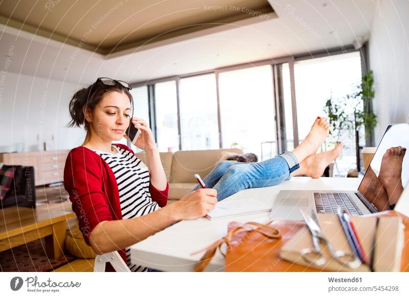 Frau am Telefon, die zu Hause am Schreibtisch arbeitet Arbeitstisch Schreibtische telefonieren anrufen Anruf telephonieren weiblich Frauen Tisch Tische